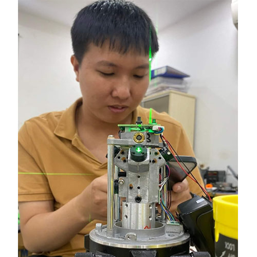Kỹ sư đang hiệu chỉnh thiết bị laser công nghiệp với hệ thống cơ khí và mạch điện tử